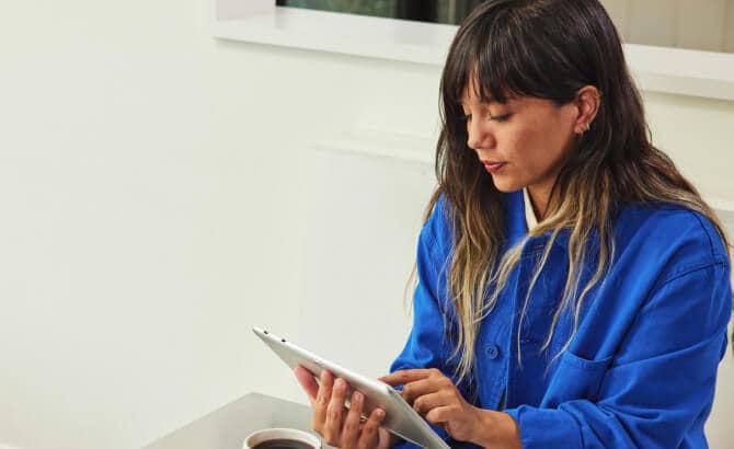 Jonge vrouw met tablet aan tafel