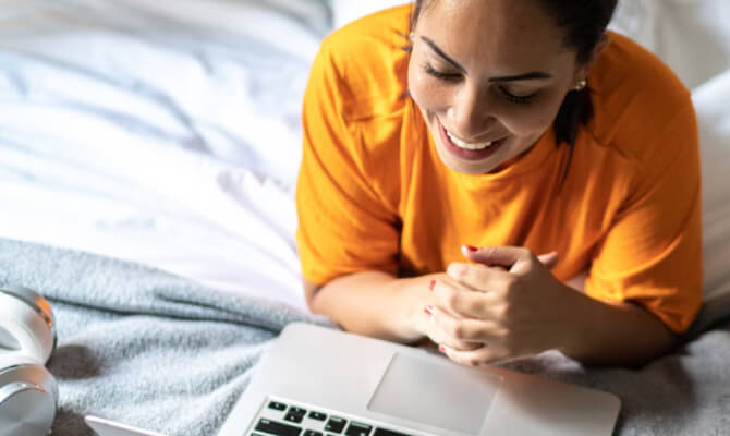 Vrouw die glimlachend naar laptop kijkt